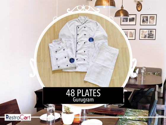 White chef coat with black buttons and piping, round logo badge and white trousers, laid flat, custom made for 48 Plates by RestroCart, New Delhi