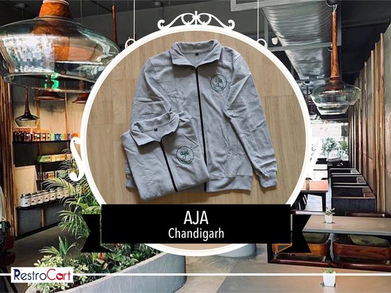Grey zip-up track jacket with black zip trim and green circular logo, laid flat, custom made for AJA by RestroCart, New Delhi