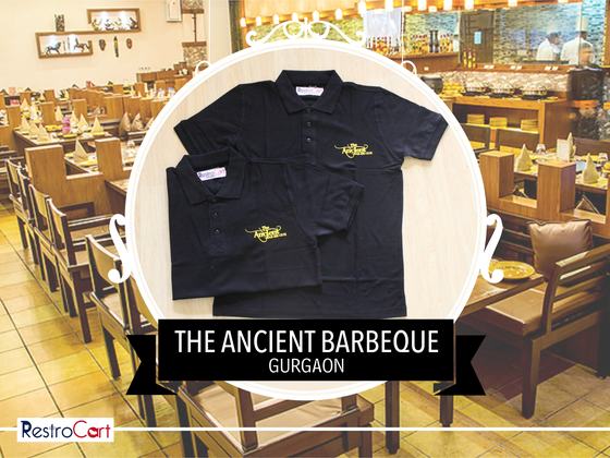 Two black polo t-shirts with yellow embroidered logo on the chest, folded, custom made for Ancient Barbeque by RestroCart, New Delhi