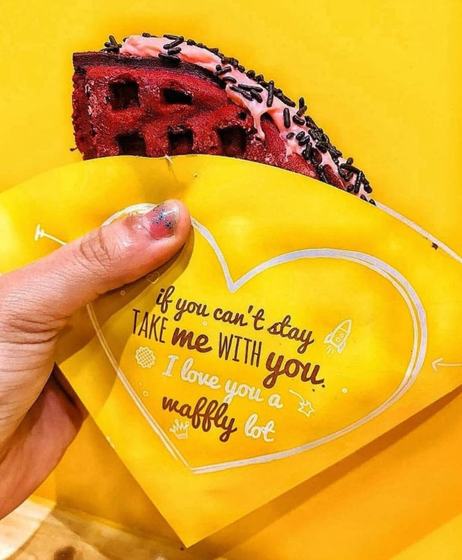 A waffle held in a yellow printed paper sleeve with a heart and the line 'If you can't stay, take me with you', custom packaging for Authentic Belgian Waffles by RestroCart