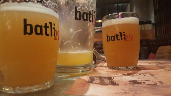 Beer mugs and pint glasses with bold black printed logo, filled with beer on a bar table, custom made for Batli 29 by RestroCart, New Delhi