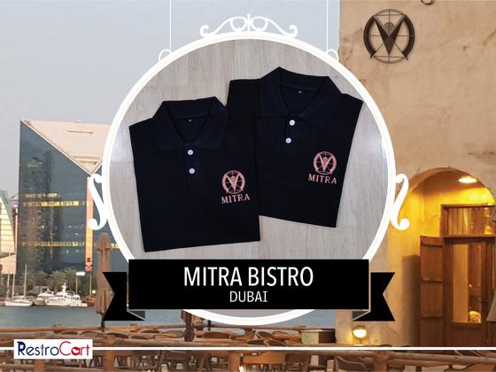 Two black polo t-shirts with copper embroidered monogram logo on the chest, folded, custom made for Bistro Mitra by RestroCart, New Delhi