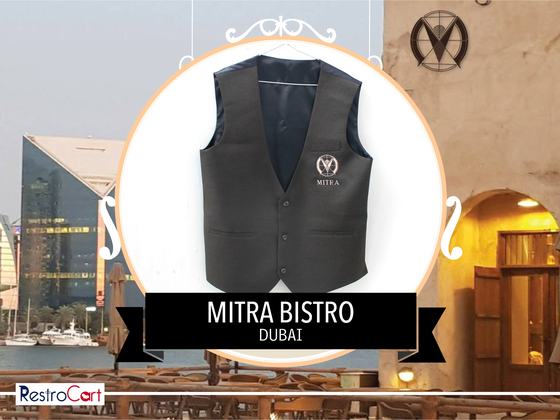 Charcoal grey waistcoat with copper embroidered monogram logo, shown upright on white, custom made for Bistro Mitra by RestroCart, New Delhi