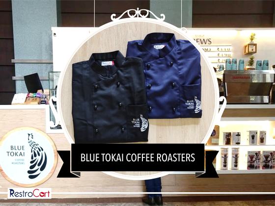 Black and navy double-breasted chef coats with small sleeve logo, folded, custom made for Blue Tokai Coffee Roasters by RestroCart, New Delhi