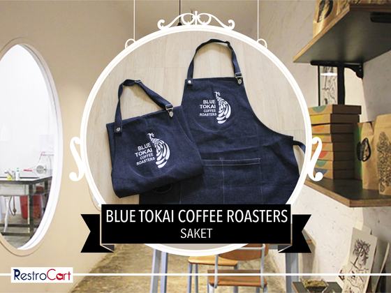Two navy denim aprons, bib and waist styles, with large white printed bird logo, custom made for Blue Tokai Coffee Roasters by RestroCart, New Delhi