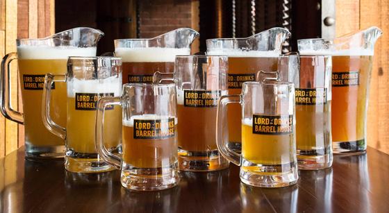 Row of glass beer mugs and pitchers with printed black and gold labels on a bar counter, custom made by RestroCart, New Delhi