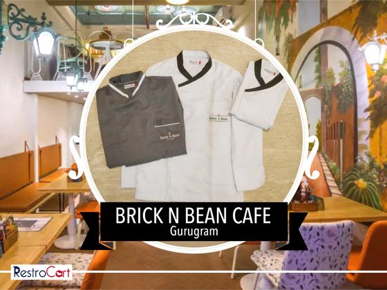 White chef coat with black collar, grey chef coat and white shirt with logo, laid flat, custom made for Brick N Bean Cafe by RestroCart, New Delhi
