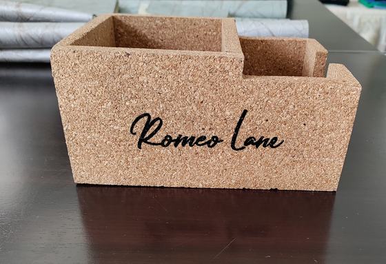 Close front view of a cork caddy with large black printed script name on a dark table, custom made by RestroCart, New Delhi