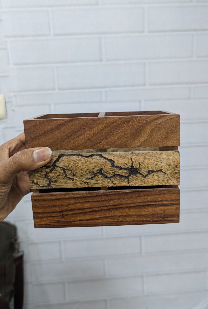 Solid wood two-compartment cutlery caddy with a contrasting centre slat carrying a dark branching inlay pattern, held in hand, made by RestroCart