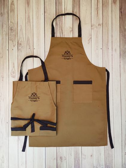 Tan canvas bib aprons in two sizes with brown straps, brown pocket trim and embroidered logo, custom made by RestroCart, New Delhi