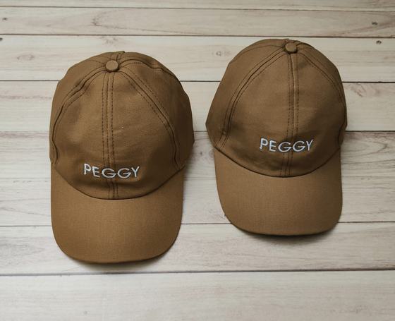 Pair of tan brown cotton baseball caps with white embroidered block letter wordmark, on wood, custom made by RestroCart, New Delhi
