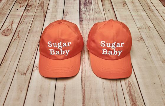 Pair of orange baseball caps with white embroidered two-line text on the front panel, custom made by RestroCart, New Delhi