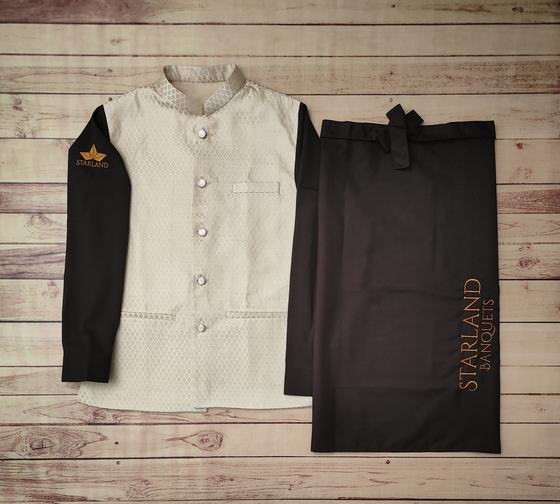 Cream textured Nehru jacket with black sleeves and orange logo beside black waist apron, custom made by RestroCart, New Delhi