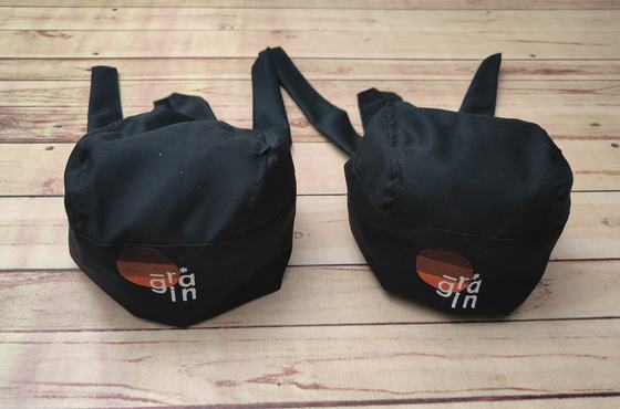 Black chef skull caps with back ties and white and orange printed logo on the band, custom made by RestroCart, New Delhi