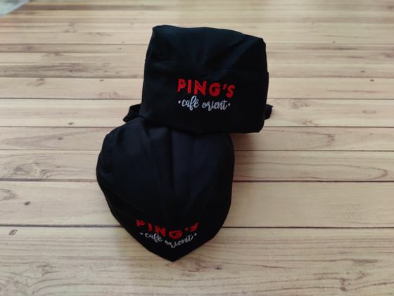 Pair of black chef skull caps with red and white printed cafe logo, one stacked on the other, custom made by RestroCart, New Delhi