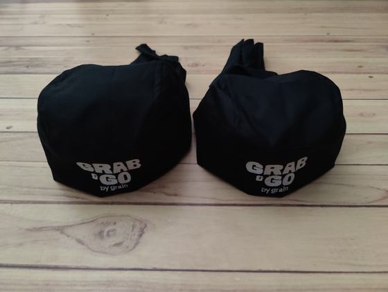 Pair of black chef skull caps with back ties and grey printed bold wordmark on the front band, custom made by RestroCart, New Delhi