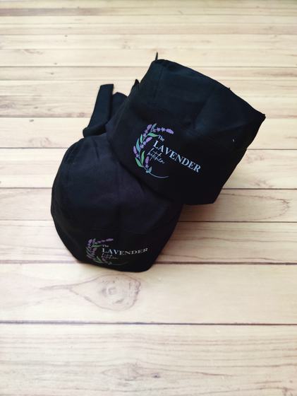 Pair of black chef skull caps with purple printed lavender sprig logo, one stacked on the other, custom made by RestroCart, New Delhi