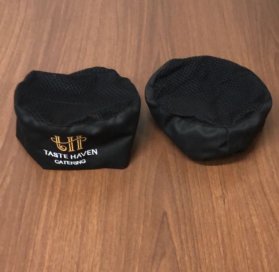 Pair of black chef skull caps with mesh crown and gold and white embroidered catering logo, custom made by RestroCart, New Delhi
