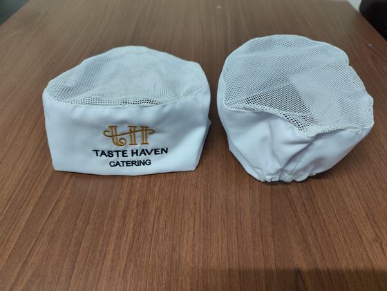 Pair of white chef skull caps with mesh crown and gold and black embroidered catering logo, custom made by RestroCart, New Delhi