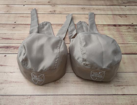 Beige chef skull caps with long back ties and white printed crest logo on the band, custom made by RestroCart, New Delhi