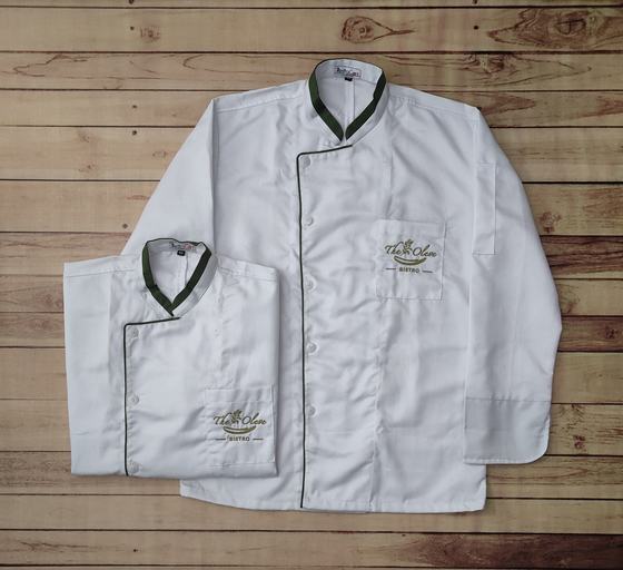 White chef coats with dark green collar, green piping and embroidered gold script logo, long and short sleeve, custom made by RestroCart, New Delhi
