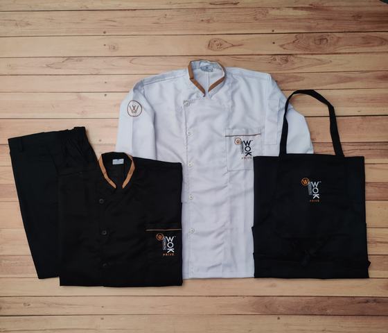 White and black chef coats with gold collar trim, black trousers and black bib apron with wok logo, custom made by RestroCart, New Delhi