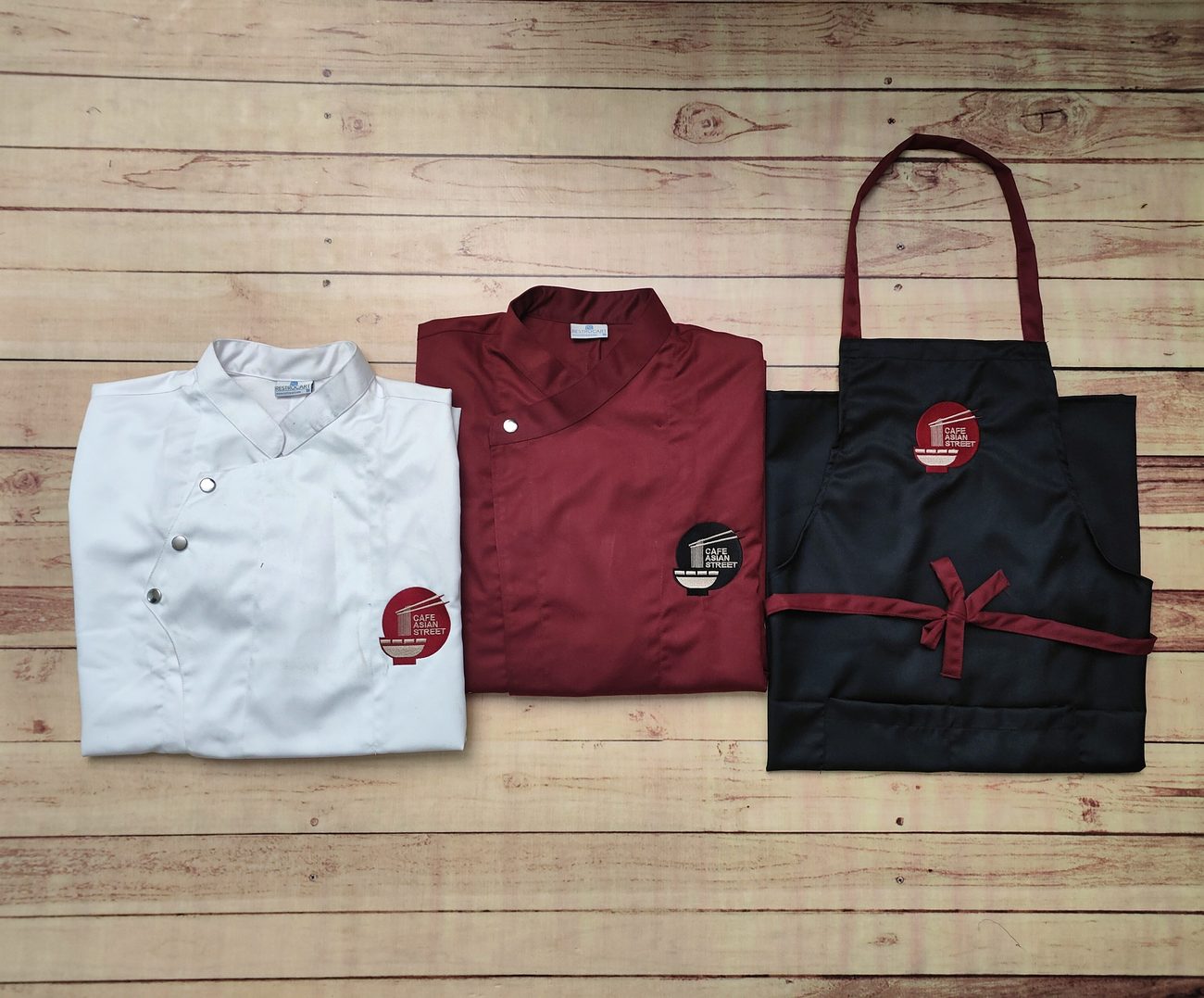 Custom white and maroon chef coats with a black embroidered apron, a complete kitchen uniform set made by RestroCart, New Delhi