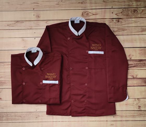 Maroon double breasted chef coats with white collar and pocket trim, gold embroidered logo, custom made by RestroCart, New Delhi