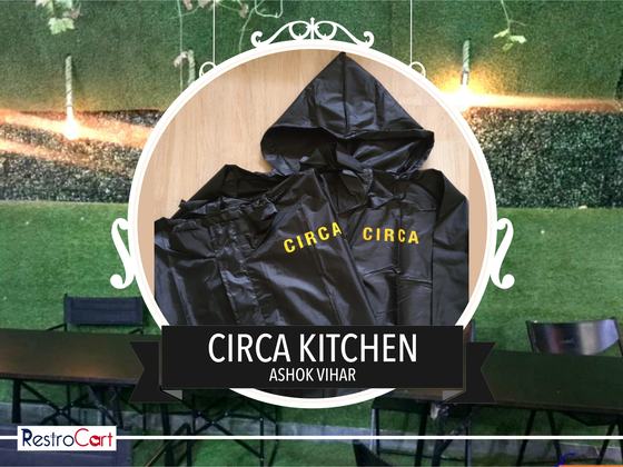 Black hooded raincoats with yellow printed wordmark across the back, laid flat, custom made for Circa Kitchen by RestroCart, New Delhi
