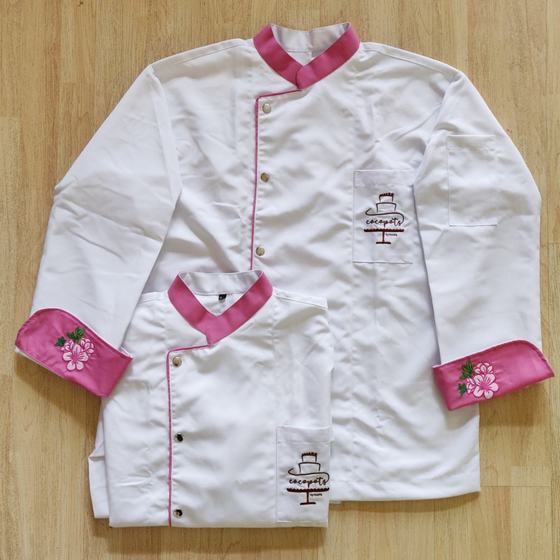 Two white chef coats with pink collars, pink piping and pink cuffs embroidered with a flower, and the Cocopots cake-stand logo on the chest pocket