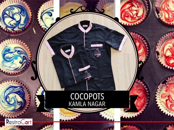 Black short-sleeve housekeeping shirts with pink collar and piping and cake logo, folded, custom made for Cocopots by RestroCart, New Delhi