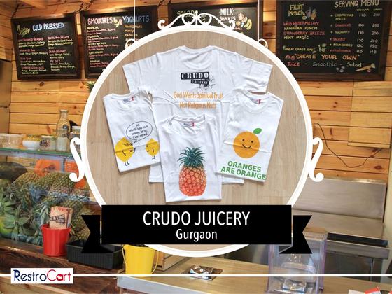 White t-shirts with colourful fruit prints including pineapple and orange, laid flat, custom made for Crudo Juicery by RestroCart, New Delhi