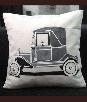 Cream cushion cover screen printed with a black line drawing of a vintage car, a custom soft furnishing for a cafe interior