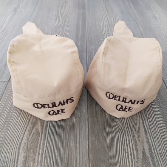 Two beige chef skull caps with black embroidered name band, custom made for Delilah by RestroCart, New Delhi