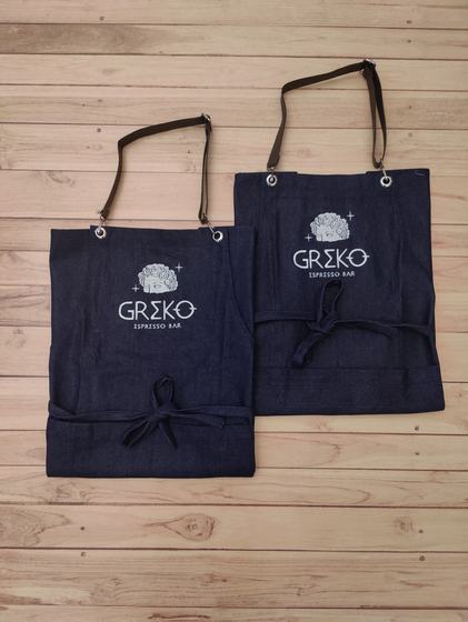 Two dark denim bib aprons with leatherette neck straps and silver printed logo, folded at the waist, custom made by RestroCart, New Delhi
