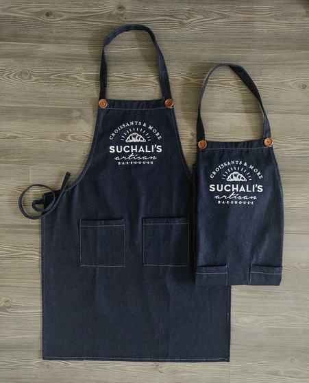Adult and kids denim bib aprons with copper buttons and white printed bakery logo, two front pockets, custom made by RestroCart, New Delhi