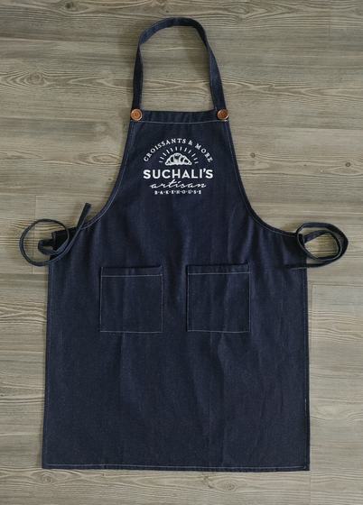 Single denim bib apron with copper button fastenings, white printed arched logo and twin front pockets, custom made by RestroCart, New Delhi