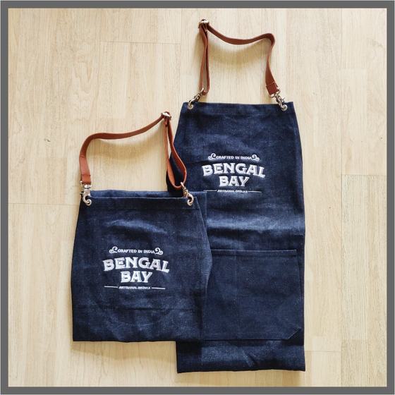 Adult and small denim bib aprons with tan leather straps and white printed bay logo, custom made by RestroCart, New Delhi
