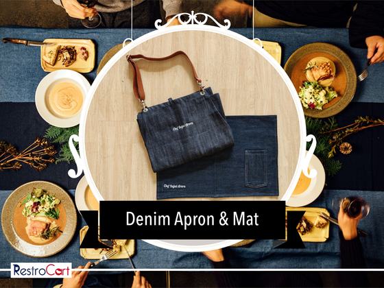 Dark denim bib apron with tan leather strap and matching denim table mat, shown on a dining table, custom made by RestroCart, New Delhi