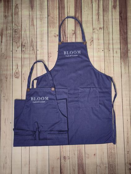 Navy denim bib aprons in two sizes with contrast stitching, pocket and white printed logo, custom made by RestroCart, New Delhi