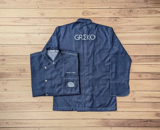 Dark denim chef coat with large white back logo and folded front coat with head chef text and pocket badge, custom made by RestroCart, New Delhi