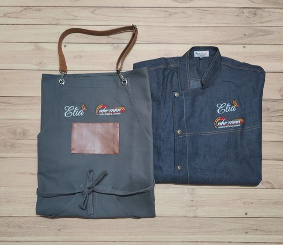 Denim chef coat with embroidered name and logo beside a grey bib apron with leather strap and patch, custom made by RestroCart, New Delhi