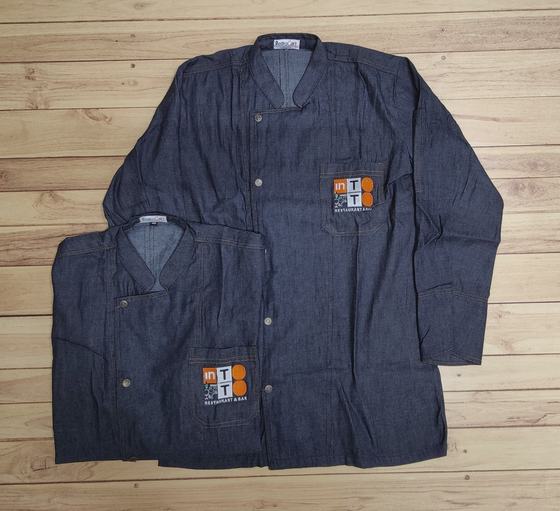 Two long-sleeve denim chef coats with snap buttons and orange square patch logo on the pocket, custom made by RestroCart, New Delhi