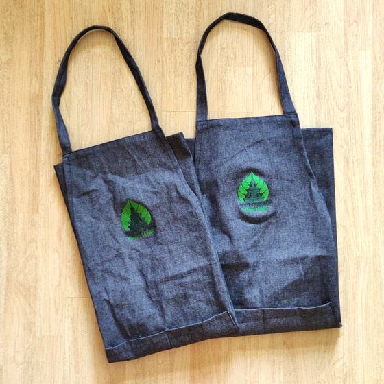 Two grey denim bib aprons with green printed leaf logo and matching neck straps, custom made for Depth N Green by RestroCart, New Delhi
