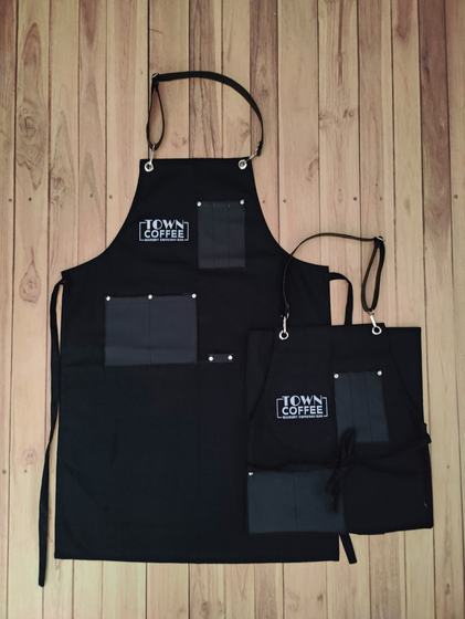 Black canvas apron pair with black leatherette pockets and boxed white text logo, custom made by RestroCart, New Delhi