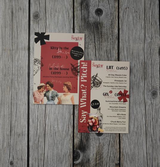 Printed paper cocktail and event menus with retro photo collage and red accents laid on grey planks, custom made by RestroCart, New Delhi