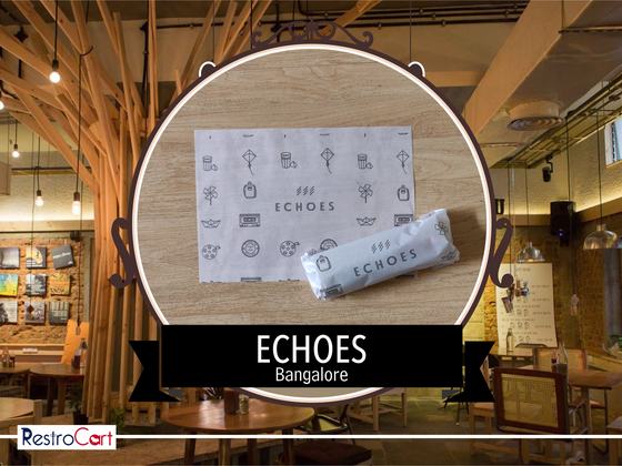 White printed paper placemat with line icons and logo beside a wrapped cutlery pouch, custom made for Echoes by RestroCart, New Delhi