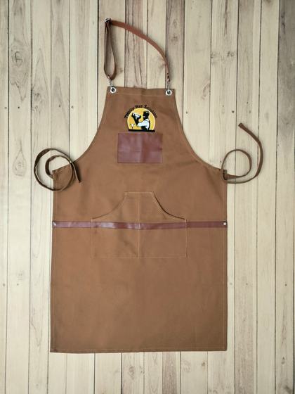 Golden brown canvas bib apron with leatherette straps, pocket trim and round embroidered logo, custom made by RestroCart, New Delhi