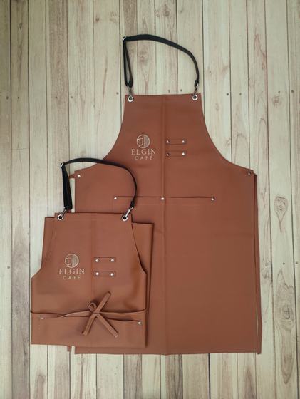 Tan leatherette bib and waist apron pair with black strap and embossed logo, light wood, custom made for Elgin Cafe by RestroCart, New Delhi