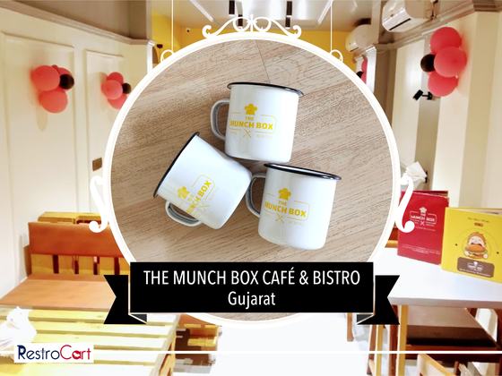 Three white enamel mugs with black rims and yellow printed logo, grouped on wood, custom made by RestroCart, New Delhi